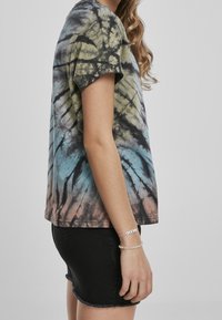 T-shirt med tie-dye i gröna, blå och rosa nyanser. Korta ärmar, rundad halsringning, avslappnad passform. Kombinerad med en svart denimkjol.