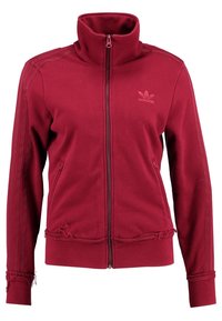 Burgundy Adidas träningsjacka med fullständig dragkedja, hög krage, dragkedjefickor på sidorna och signaturtrestreck på ärmarna, med lätt fransade detaljer.