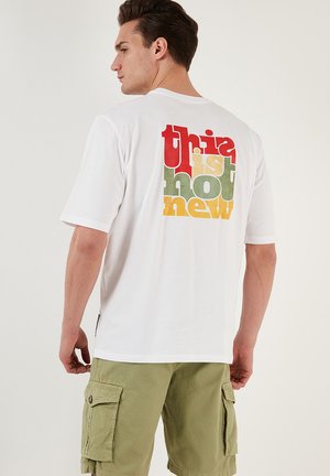 White short-sleeve t-shirt featuring multicolored text on the back: "this is not new" in red, green, yellow, and orange.