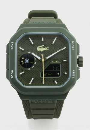 Zelené hybridní hodinky Lacoste s analogovými ručičkami, digitálním displejem, indikátorem dne a texturovaným silikonovým páskem s logem Lacoste.