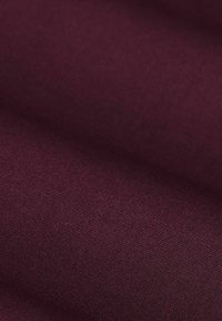 Close-up van opgevouwen, fijn gestructureerde stof in diep bordeauxkleur.