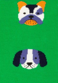 Calcetines verdes con dos caras de perro: una cara superior multicolor con orejas naranjas y una máscara azul, y una cara en blanco y negro debajo.