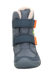 Niebieski materiałowy but z dwiema regulowanymi rzepami, futrzanym wykończeniem na górze i zakrzywioną podeszwą. Zawiera jaskrawe zielone i pomarańczowe akcenty.