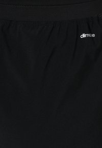 Tissu noir en gros plan avec une ceinture élastique et un petit texte blanc "climate" imprimé près du côté supérieur droit.