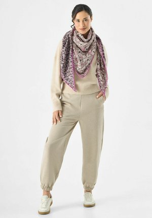 Pull en tricot beige, joggers assortis, et une écharpe à motifs avec des accents roses, comprenant un mélange de motifs animaliers dans des couleurs atténuées.