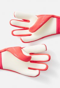 Gants rouges en matériau texturé et doux. Présentent un design sans doigts avec des embouts ouverts, des coutures renforcées et une étiquette "Dynamic Fit" sur le pouce.