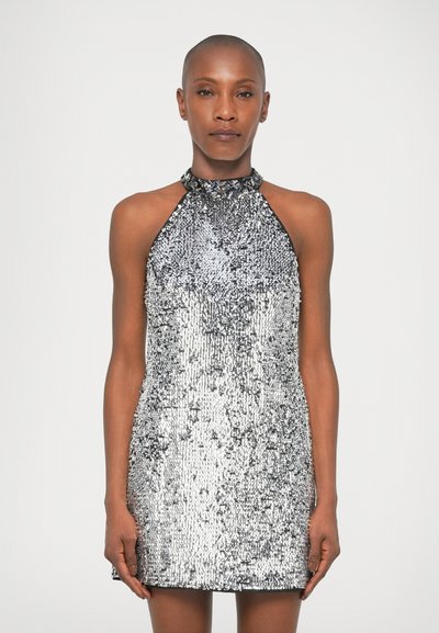 Robe halter en argent ornée de sequins, présentant une silhouette cintrée et une surface texturée, réfléchissant la lumière dans des motifs variés.