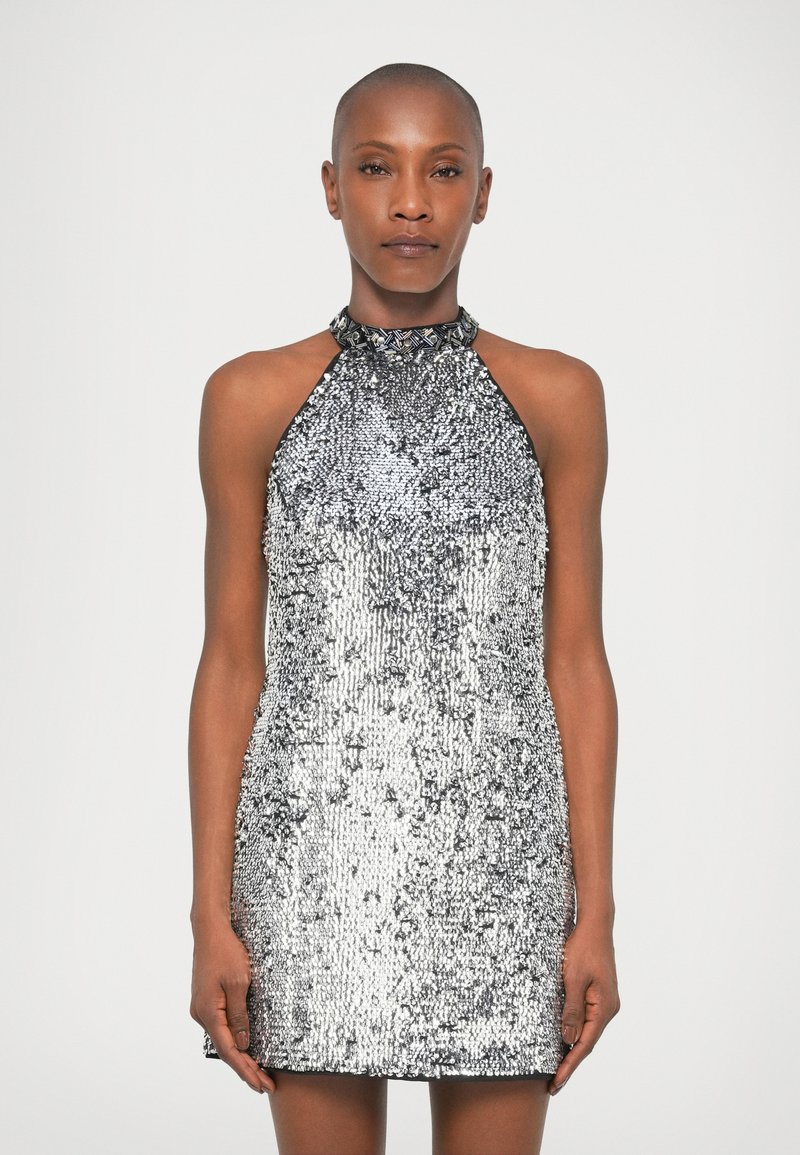 Silbernes Halterneck-Kleid, das mit Pailletten verziert ist, mit einer figurbetonten Silhouette und strukturiertem Material, das das Licht in verschiedenen Mustern reflektiert.