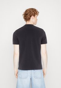 Svart kortermet t-skjorte med rund hals, laget av bomull. Designet med en vanlig passform, glatt tekstur og minimale sømmer.