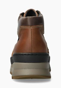 Bottine en cuir marron avec un dos arrondi, semelle noire contrastante et semelle intermédiaire beige. Présente des détails cousus et une texture lisse.