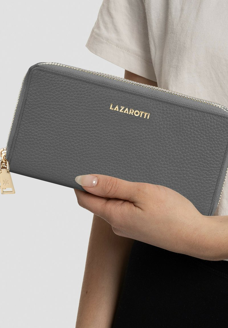 Cartera de cuero texturizado gris con herrajes dorados y marca. Presenta un cierre con cremallera y un acento de llavero en el tirador de la cremallera.