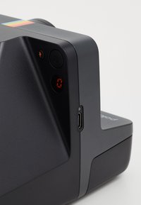 Instant camera with a matte black finish, featuring button controls, a red digital display, and a USB-C port on the side.