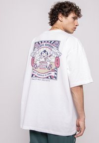 White short-sleeve t-shirt featuring a colorful graphic on the back of a ramen character with text and decorative elements.