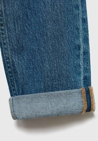 Blå denimjeans med rak passform och uppvikt fåll. Tyget har en mjuk yta med kontrasterande sömmar längs fållen.
