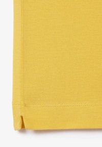 Gult textilt tyg med en strukturerad yta, som har en vikning och snygg söm. Materialet verkar hållbart och lätt.