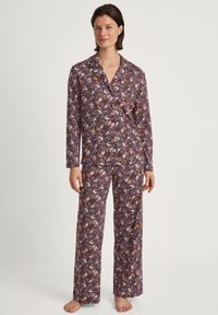 Paarse pyjama set met lange mouwen, met een speels patroon van vogels en bloemen. Gemaakt van zachte stof met een overhemd met knopen en losse broek.