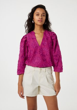 Magenta geborduurde blouse met een V-hals, bloemmotieven en puffed sleeves, gecombineerd met witte shorts. Glad textuur, casual ontwerp.