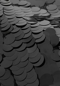 Black circular sequins arranged closely together, varying slightly in size, with a glossy surface and small holes for attachment.