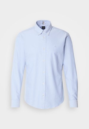 Šviesiai mėlynas marškinėlių užsegamas marškiniai su apykakle, ilgomis rankovėmis ir siuvinėtu logotipu kairėje krūtinės pusėje. Minkšta medžiaga su lygiu paviršiumi.