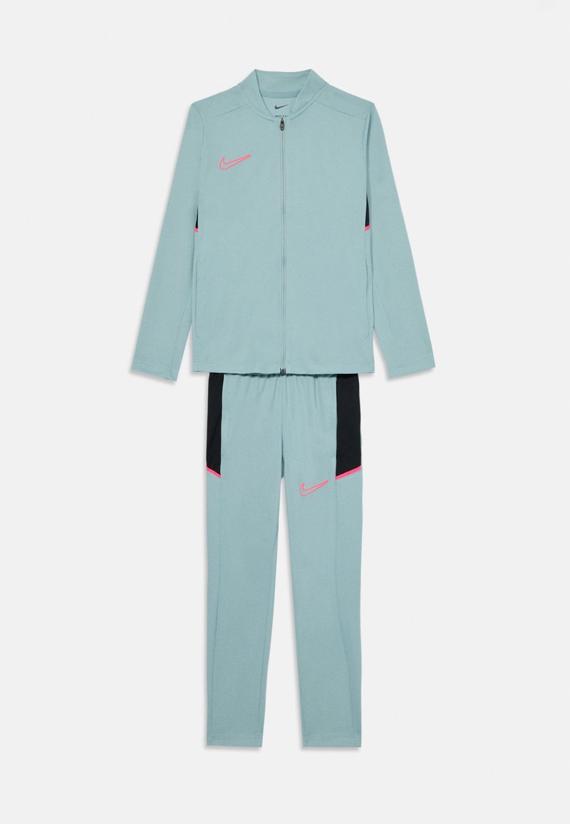 Survêtement Nike bleu clair composé d'une veste zippée et d'un pantalon à taille élastique, avec des accents roses et noirs sur les côtés et le logo.