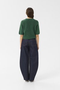 Green knitted sweater with short sleeves paired with wide-leg dark blue denim jeans. Jeans feature back pockets and a classic cut.
