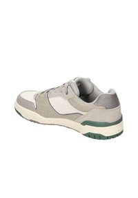 Buty sportowe z beżowych i szarych materiałów syntetycznych, teksturowana cholewka oraz zielona gumowa podeszwa z perforowanymi akcentami zapewniającymi wentylację.