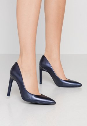 Chaussures à talons hauts en cuir verni bleu marine avec bout pointu et détails découpés. Talon aiguille fin, texture lisse et design élégant.