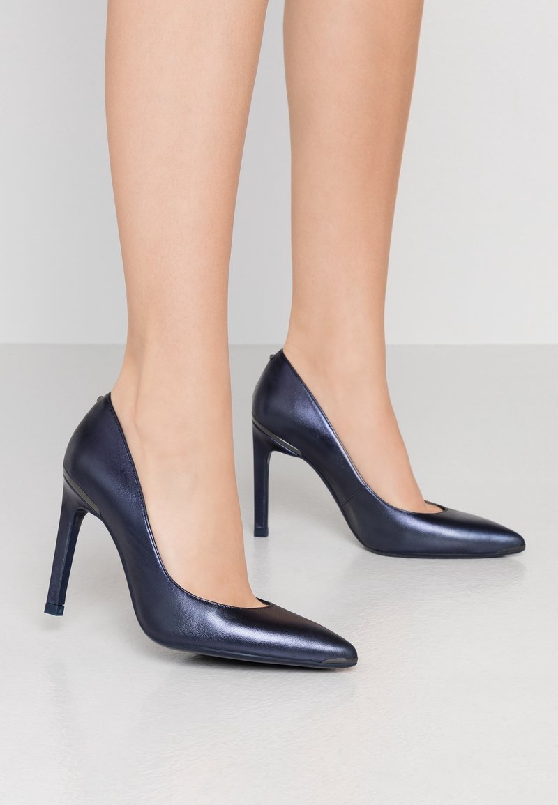 Chaussures à talons hauts en cuir verni bleu marine avec bout pointu et détails découpés. Talon aiguille fin, texture lisse et design élégant.