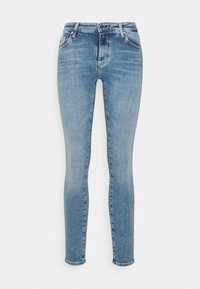Jeans ajustados en denim azul claro, con un diseño clásico de cinco bolsillos, cierre de cremallera con botón y una textura ligeramente desgastada.