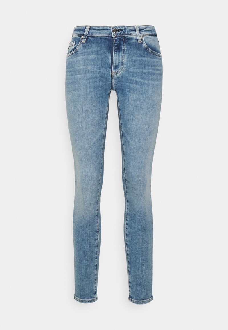 Jeans ajustados en denim azul claro, con un diseño clásico de cinco bolsillos, cierre de cremallera con botón y una textura ligeramente desgastada.