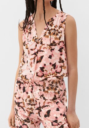 Woman wearing sleeveless pink floral top and matching elastic waist pants with brown and black abstract patterns.