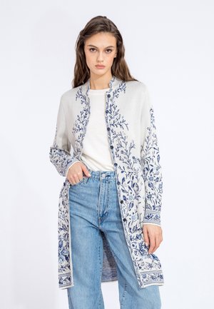 Cardigan lungo aperto color crema con intricate ricami floreali blu e orli a contrasto. Tessuto morbido, vestibilità rilassata e tasche laterali.