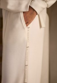 Witte geribbelde joggers van stof met een zijzak, voorzien van een logolabel dat 'b by Ted Baker' langs de naad leest.