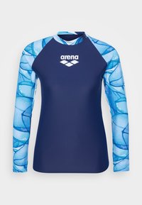 Langermet svømmeshirt laget av elastisk materiale, med en marineblå kropp og blå mønstrede ermer med en hvit logo sentrert på brystet.