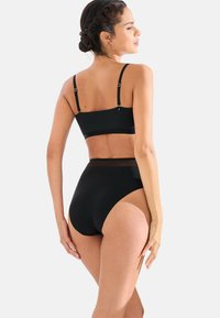 Maillot de bain deux pièces noir comprenant un haut bralette avec des bretelles réglables et un bas taille haute. Le matériau a l'air lisse avec un design minimaliste.