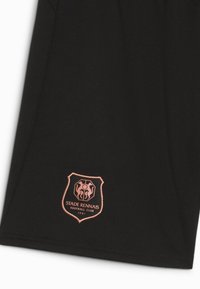 Svarta sportshorts med en strukturerad tygkvalitet. En rosa broderad logotyp i sköldform visar "STADE RENNAIS FOOTBALL CLUB" längst ner.