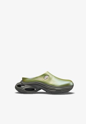 Pantof slip-on verde cu talpă groasă neagră, cu secțiuni decupate, partea superioară netedă și o mică decupare ovală lângă călcâi.