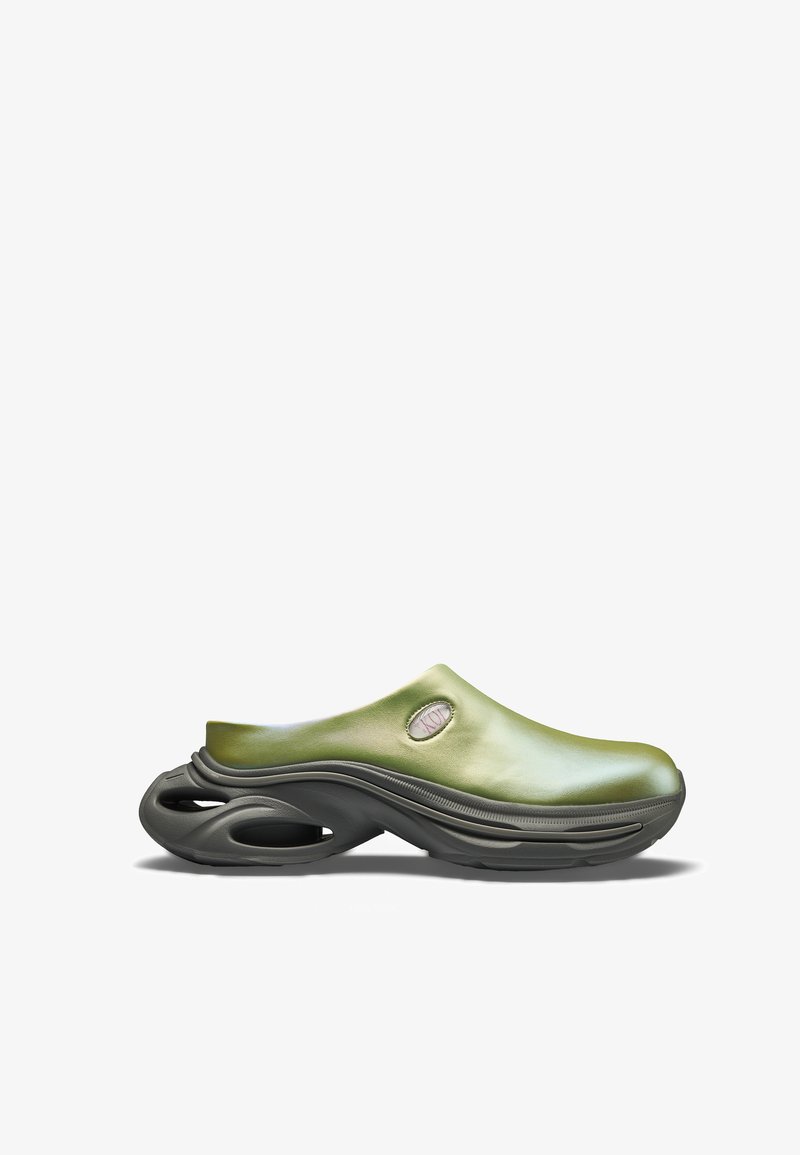 Grüner Schlupfschuh mit dicker schwarzer Sohle, die ausgehöhlte Bereiche aufweist, glattem Obermaterial und kleinem ovalem Ausschnitt nahe der Ferse.