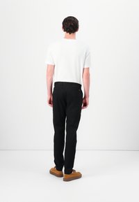 White short-sleeve t-shirt, black slim-fit trousers, and brown suede shoes. Smooth fabric, tailored design, and a simple, modern look.