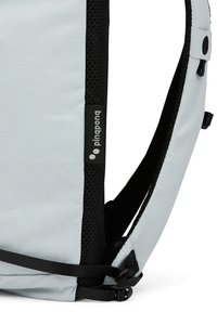 Hellgrauer Rucksack mit schwarzen Akzenten, ausgestattet mit einem strukturierten Mesh-Schultergurt und einem Logoschild. Inklusive verstellbarer Riemen und Schnallen.