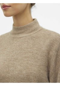 Beige polotröja med ribbat mönster, mjukt ullmaterial och en figurnära design. Halsringningen är hög och välavslutad.