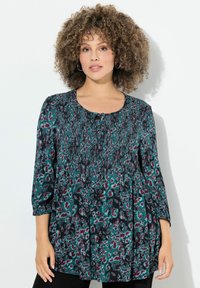 Túnica de manga larga en color azul verdoso, con un estampado animal en negro y burdeos, cuello con cordón y tejido texturizado con detalles plisados.