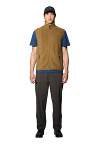 Bruine fleece vest met een hoge kraag, rits aan de voorkant en twee zijzakken, gedragen over een blauwe T-shirt en gecombineerd met donkere broeken en schoenen.