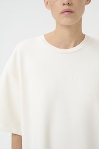 Prevelik, kratkosvijetli T-majica od off-white tkanine s rebrastim okruglim izrezom. Ima izvezeni logo u suptilnoj nijansi na prednjem dijelu.