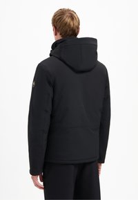 Zwarte gewatteerde jas met een capuchon, met een soepele textuur, een getailleerd ontwerp en zichtbare stiksels. Logopatch op de mouw.