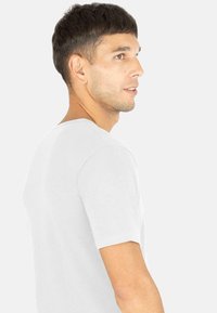 Weißes T-Shirt mit kurzen Ärmeln und Rundhalsausschnitt, aus weichem Stoff gefertigt, mit lockerer Passform und dezenten Nähten.