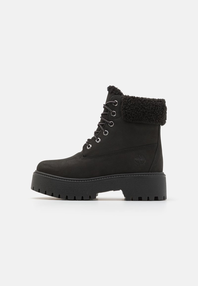 Botas negras hasta el tobillo con un puño de piel sintética, cordones en la parte delantera y una suela de goma gruesa y texturizada con profundos relieves para un mejor agarre. Diseño atemporal y duradero.