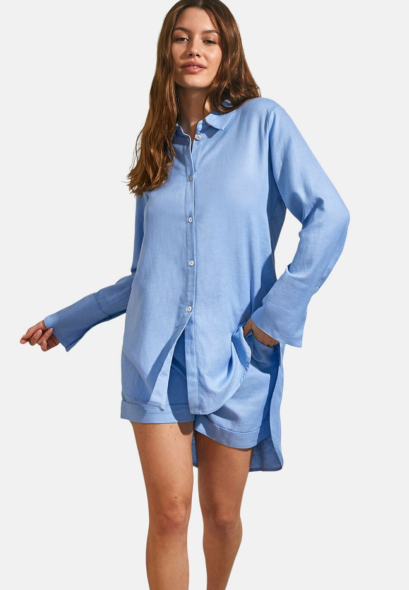 Lichtblauwe button-up shirt gemaakt van zachte stof, met een ontspannen pasvorm, lange mouwen en zijzakken, gecombineerd met bijpassende shorts.