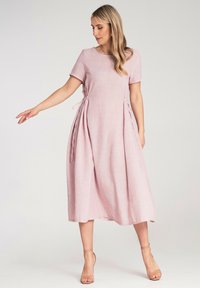 Lässiges rosa Leinenkleid mit kurzen Ärmeln, in der Taille mit Bändern gerafft, A-Linien-Silhouette, fällt unter das Knie, glatte Textur.