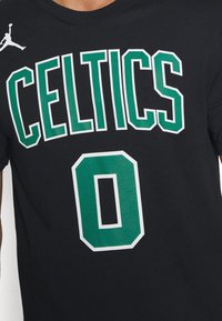 Chemise noire avec texte vert et blanc "CELTICS" et un grand numéro vert "0" en dessous, avec un petit logo Jumpman blanc.